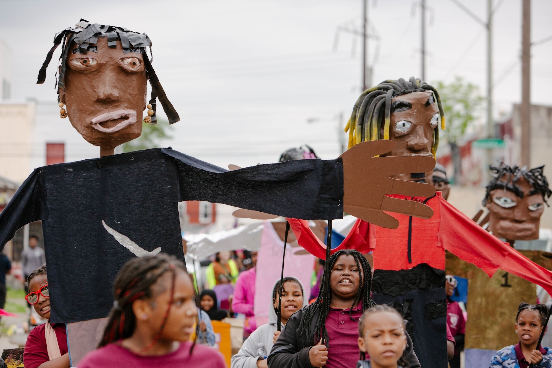 children holding paper mache puppets during a parade
