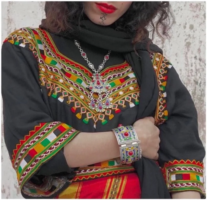 a woman wearing an Algerian kaftan, jewelry and facial tattoos