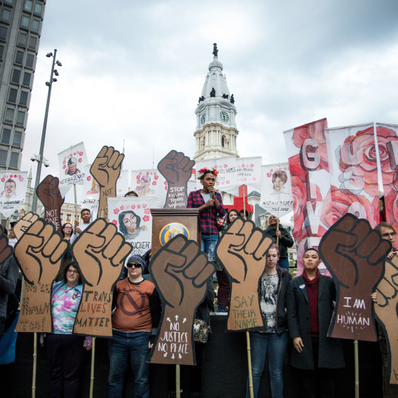 a rally in front of Philly's city hall with a group of people holding cut out signs of fists