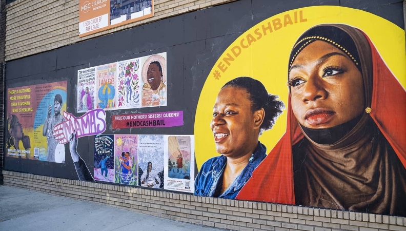 a post pasted on a city wall of two women smiling as they look into the distance