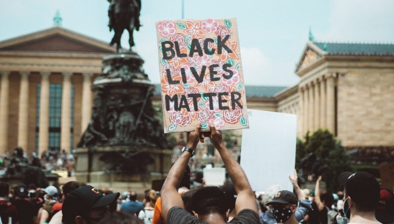 a man holds a Black Lives Matter sign at a protest in front of the Philadelphia Art Museum