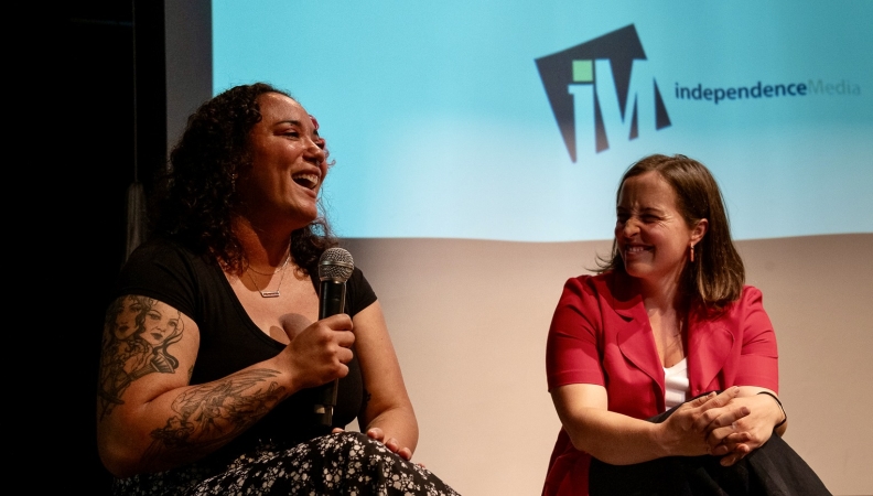 a person holds a microphone while laughing during a panel conversation