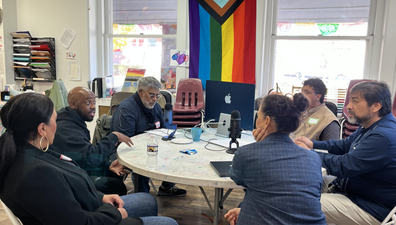 a group of people seated around a table recording a podcast episode
