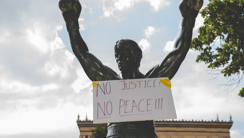 image of Rocky statue with a sign on it saying no justice, no peace