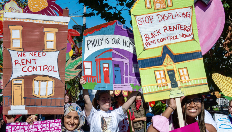 a group of protesters holding artfully made signs about the need for rent control in Philly