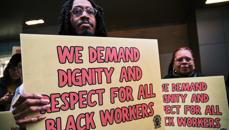 Black workers at a rally holding sign posts