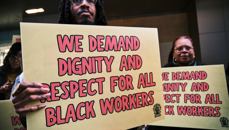 Black workers at a rally holding sign posts