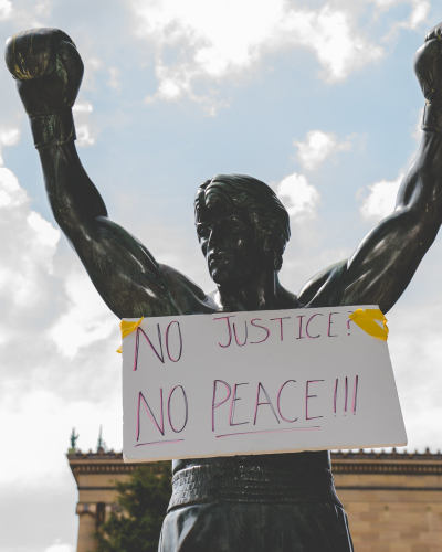 image of Rocky statue with a sign on it saying no justice, no peace