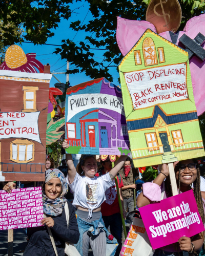a group of protesters holding artfully made signs about the need for rent control in Philly