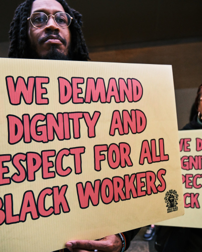 Black workers at a rally holding sign posts