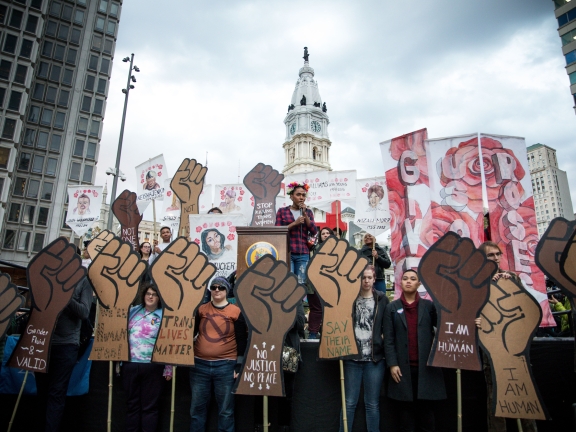 a rally in front of Philly's city hall with a group of people holding cut out signs of fists