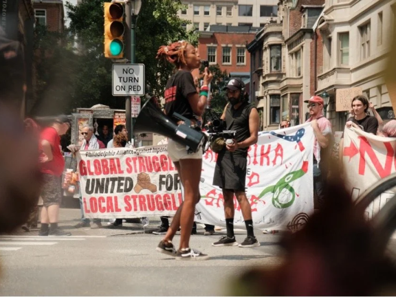 a woman holds a megaphone at a pro-Palestine rally while a man films her 