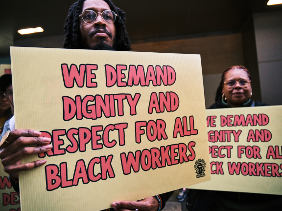 Black workers at a rally holding sign posts