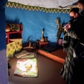 Two people inside a small room with blue walls taking pictures of the art