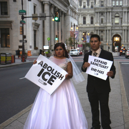 a couple dressed for their wedding hold signs that read "abolish ICE" and "expand sanctuary" 