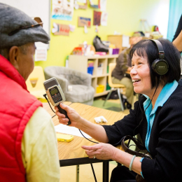 a person holds a microphone while interviewing another person wearing a red vest