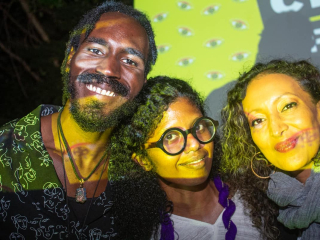 Three people posing for a picture with a yellow background projected onto them
