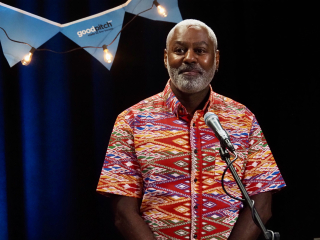 man standing behind a microphone looks out to an audience